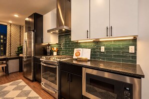 A modern kitchen with stainless steel appliances, green backsplash tiles, and a built-in oven. - Stunning Lux Nash Home | Rooftop Firepit | 10 Beds (Nashville)