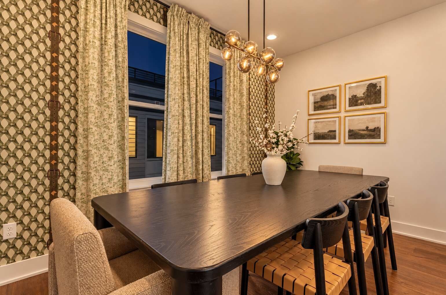 A dining area with a dark wooden table, black chairs, and a vase with flowers.