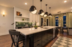 A modern kitchen with a large island, pendant lighting, and a patterned backsplash. - Stunning Lux Nash Home | Rooftop Firepit | 10 Beds (Nashville)