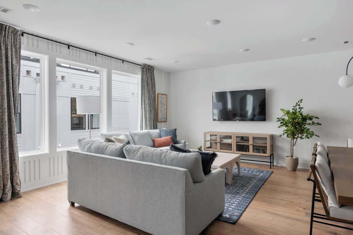A modern living room with a grey sofa, a wooden coffee table, a TV, and a potted plant.