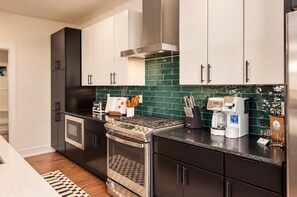 A modern kitchen with stainless steel appliances, a gas stove, and a coffee maker. - Chic Nash Retreat|Private Rooftop, Hot Tub & Views (Nashville)