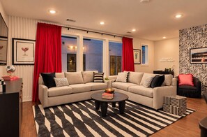 A modern living room with a sectional sofa, a coffee table, and a patterned rug. - Chic Nash Retreat|Private Rooftop, Hot Tub & Views (Nashville)