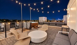 A rooftop terrace with string lights, a hot tub, and outdoor seating. - Chic Nash Retreat|Private Rooftop, Hot Tub & Views (Nashville)