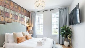 Een moderne hotelkamer met een groot bed, een kroonluchter, een flatscreen televisie en uitzicht op de stad.