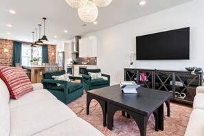 A modern living room with a sofa, armchairs, a coffee table, and a TV mounted on the wall. - Upscale 4BR Home w/Rooftop, Hot Tub & Views!7 Beds (Nashville)