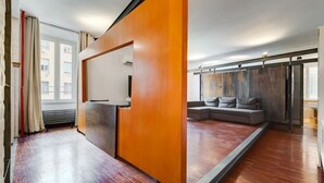 Un salon moderne avec un plancher en bois, un canapé et une grande fenêtre.