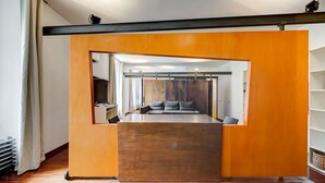 Une pièce moderne avec une plateforme centrale en bois, un canapé avec des coussins et un mur recouvert de miroirs.