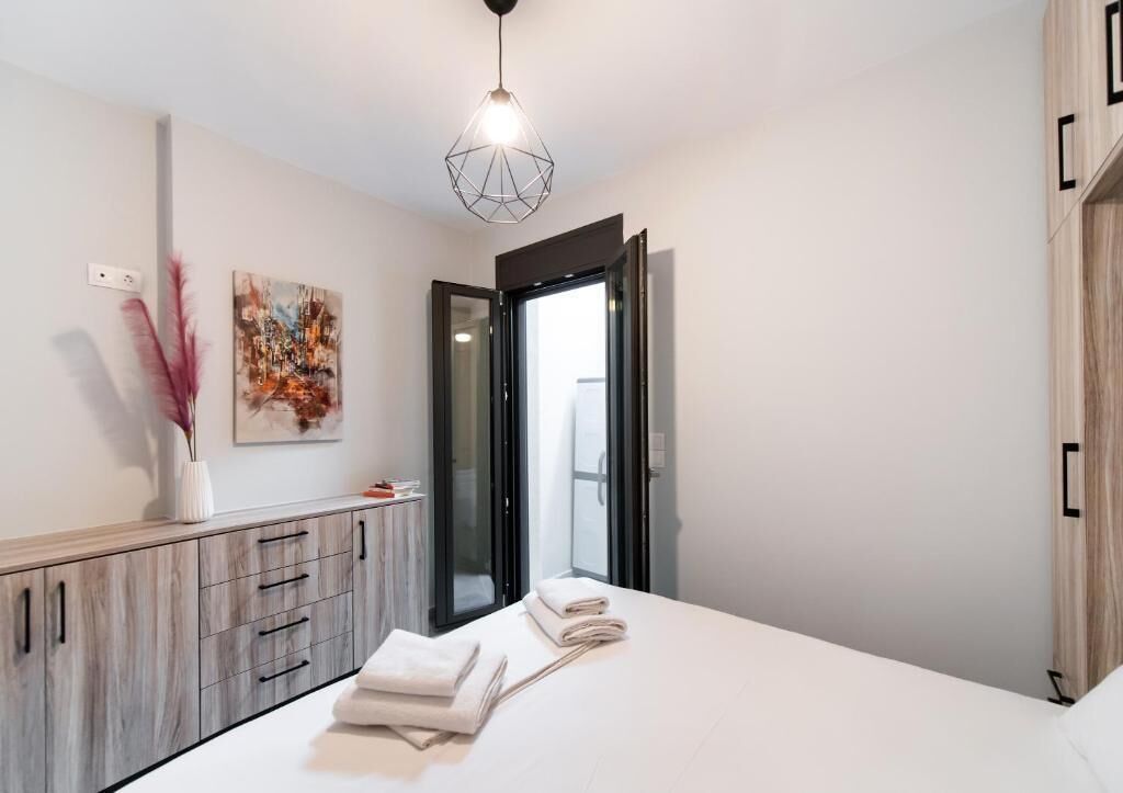 A modern bedroom with a bed, a vanity with a mirror, and a painting on the wall.