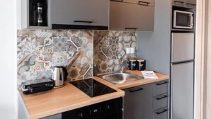 Une cuisine moderne avec des meubles gris, un four encastré, un micro-ondes et un évier.