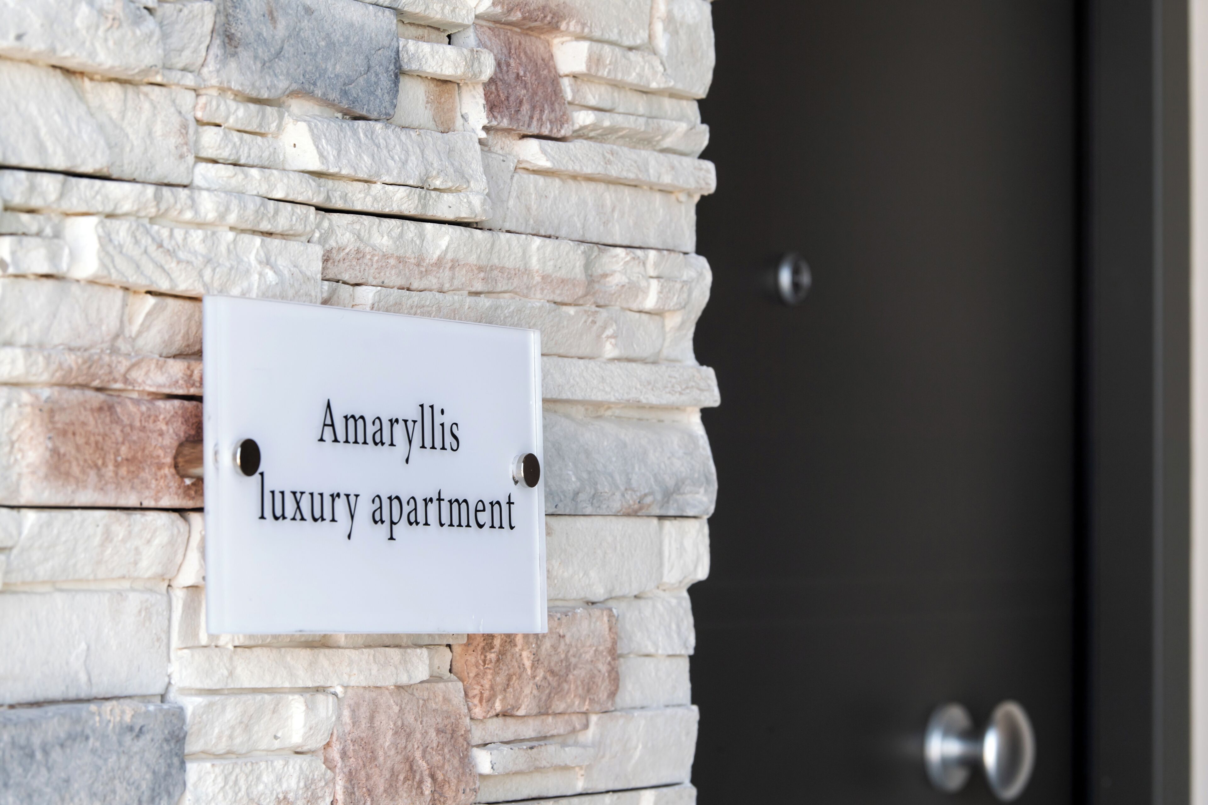 A sign on a stone wall that reads "Amaryllis luxury apartment."
