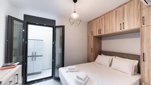 Une chambre moderne avec un grand lit, une armoire en bois et une porte vitrée donnant sur un balcon.