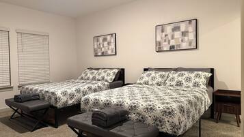 A room with two beds, each with a matching pillow and a bench. There are two framed pictures on the walls.
