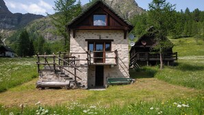 Ein Steinhaus mit einem hölzernen Balkon und einer Holztreppe, die zu einer Tür führt.