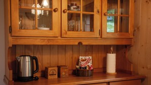 Eine Holz-Küche mit Kaffeemaschine, einer Snack-Korb und einer Küchenpapierrolle auf der Arbeitsfläche.