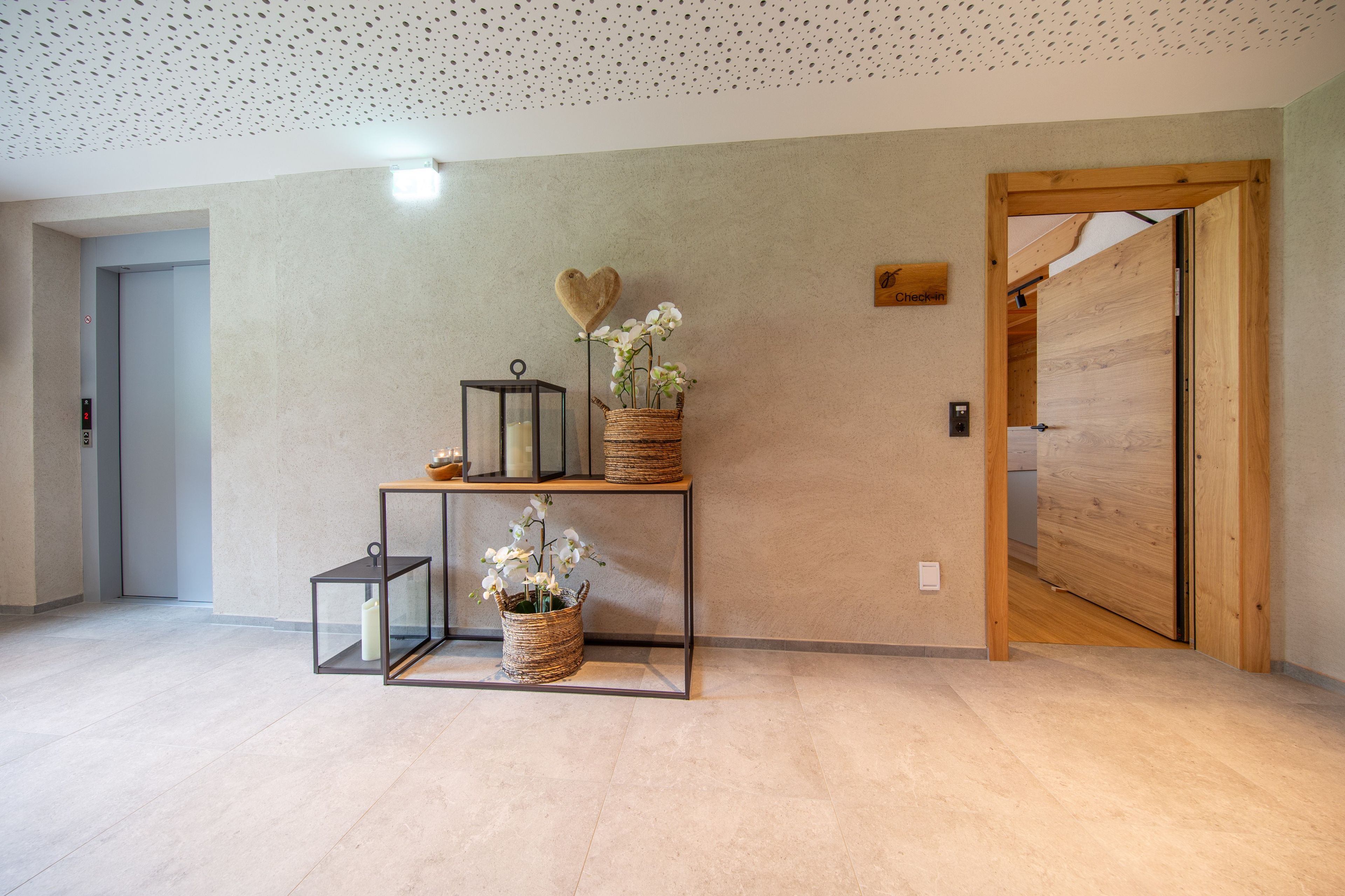 A hallway with a wooden door, a wall-mounted sign, and a shelf with decorative items.
