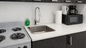 A modern kitchen with dark cabinets, a stainless steel sink, a gas stove, a coffee maker, and a microwave. - Miami Beach Cozy 1 bedroom Steps to Sand (Miami Beach)