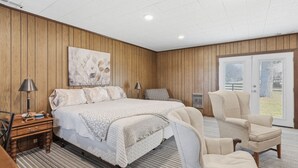 Ein Schlafzimmer mit Bett, Nachttischen, einem Sessel und einem großen Fenster.