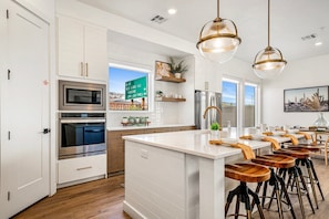 A modern kitchen with white cabinetry, stainless steel appliances, and a central island with bar stools. - 3837, Private Pool, Private Hot Tub, Fire Pit, and More! (Washington)