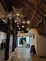 Un interior rústico con techo de paja, vigas de madera y luces colgantes con forma de estrella.