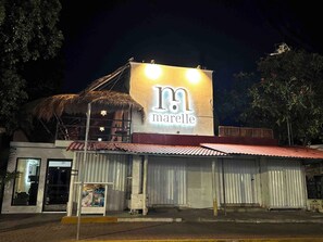 A building with a large illuminated sign reading 'maelle' and a thatched-roof structure. - Marelle Hotel Boutique (Playa del Carmen)