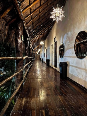 A corridor with wooden flooring, a thatched roof, and star-shaped lights. - Marelle Hotel Boutique (Playa del Carmen)
