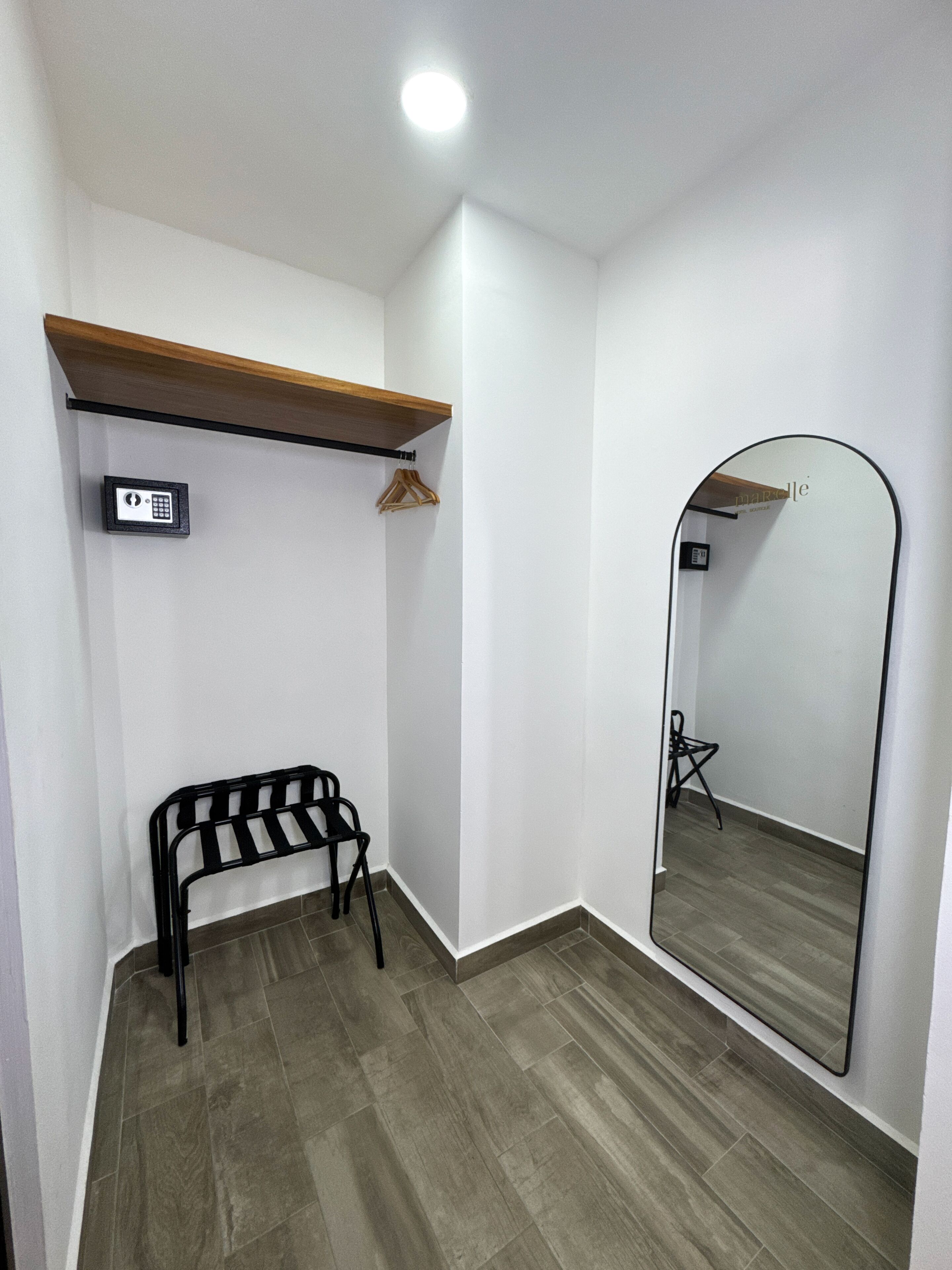 A room with a bench, a mirror, a wooden shelf, and a security keypad.