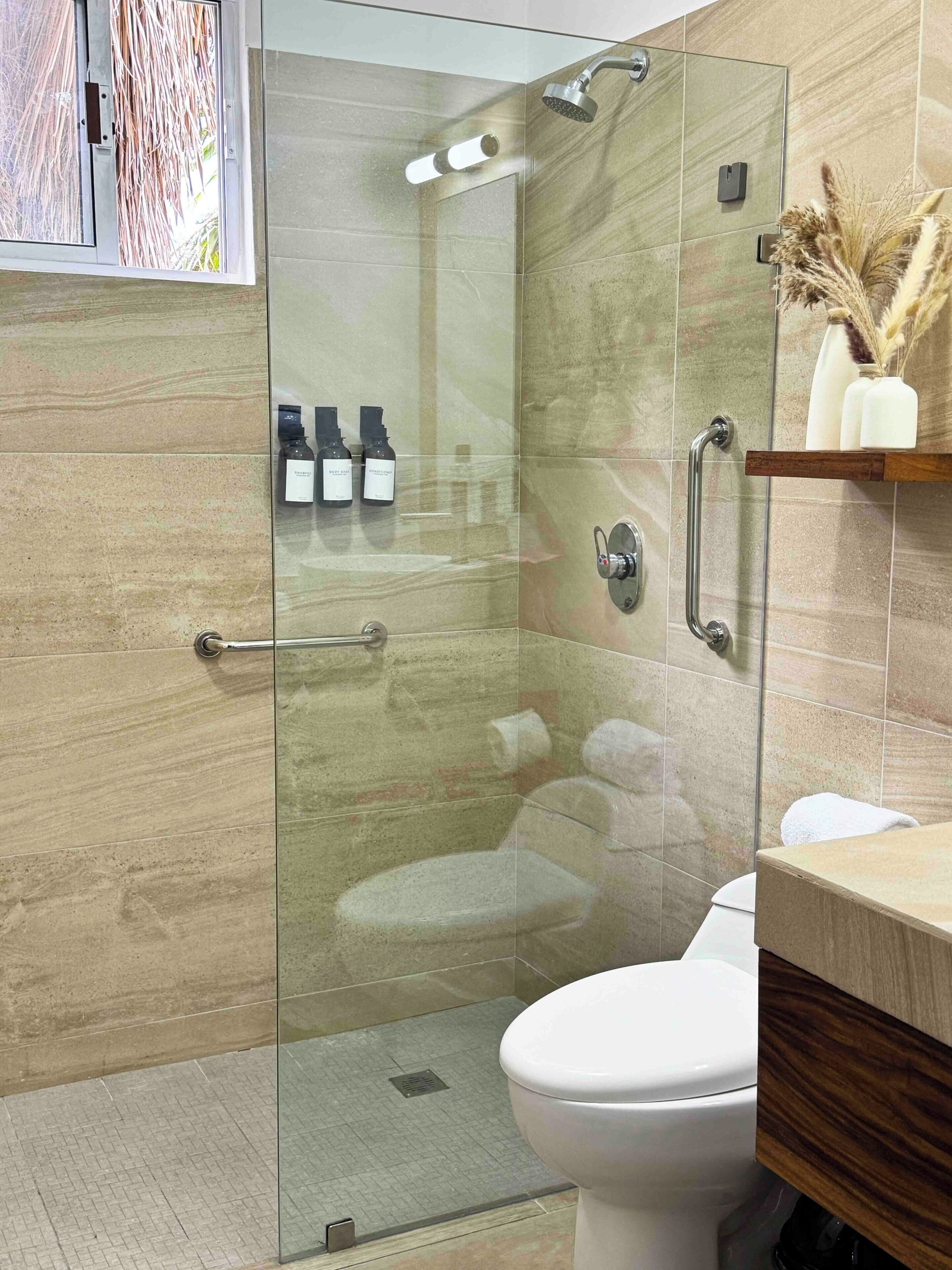 Une salle de bain moderne avec une douche à parois de verre, des toilettes et un meuble-lavabo avec un miroir.