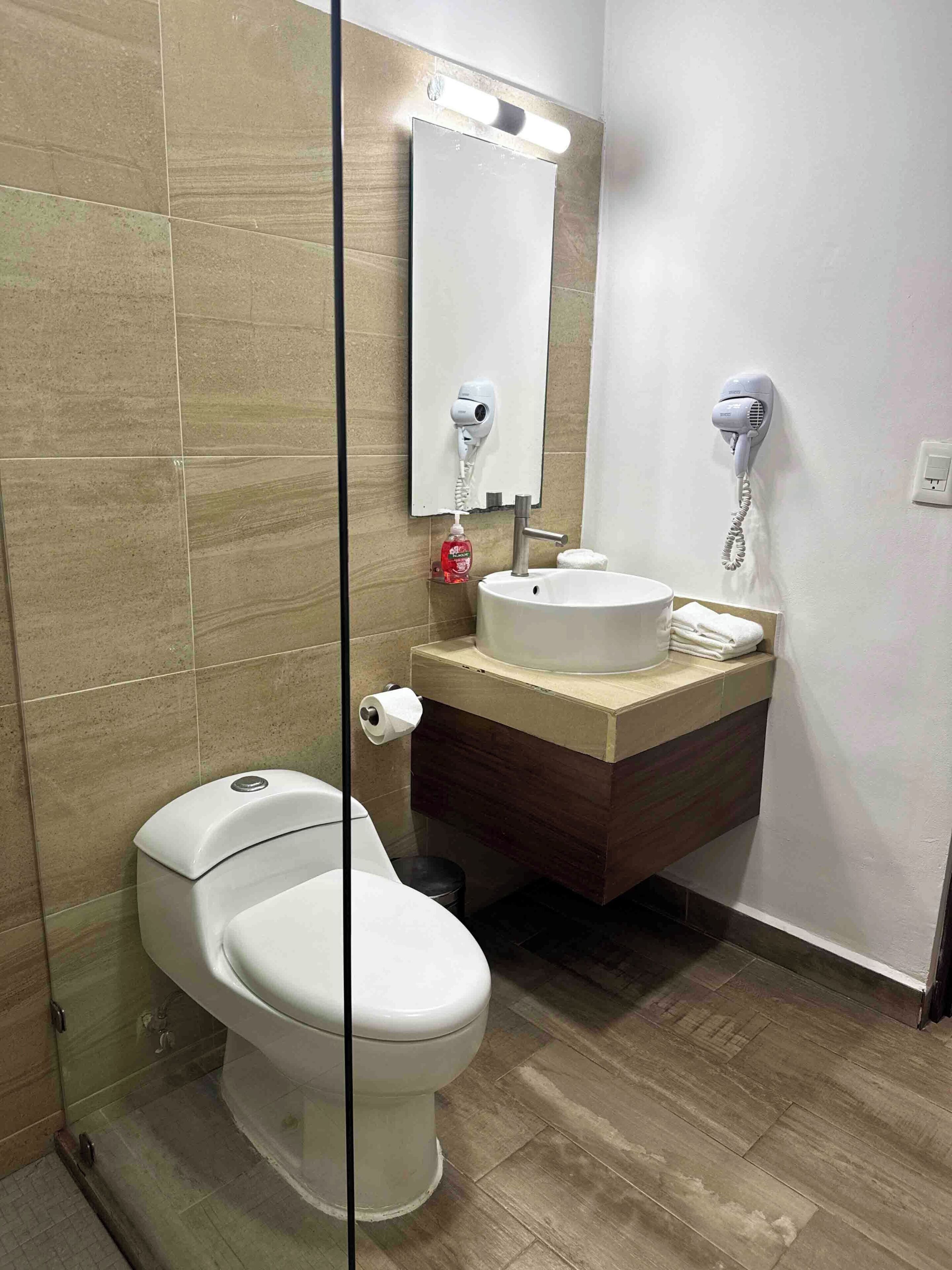 Ein Badezimmer mit Toilette, Waschbecken, Spiegel und Fön.