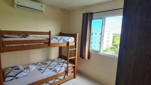 Una habitación con dos literas, una ventana con cortinas y un equipo de aire acondicionado.