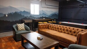 Een kamer met een bergmuur, een bank, een stoel, een salontafel en een projectiescherm.