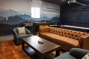 Quarto com um mural de montanhas, um sofá, uma poltrona, uma mesa de centro e uma tela de projeção.