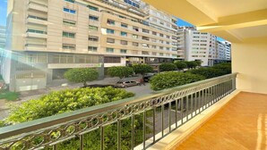 Un immeuble à plusieurs étages doté de balcons, donnant sur la rue et agrémenté de verdure.