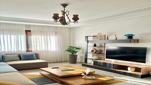 Un salon moderne avec un canapé d’angle, un téléviseur à écran plat et une table basse.