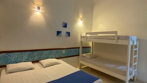 Una habitación con una litera y una cama individual, ambas con ropa de cama blanca y detalles azules. Hay dos luces fijadas a la pared y un cabecero decorativo azul y blanco.