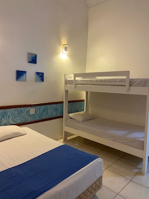 A bunk bed room with a blue bedspread, a wall-mounted light, and three small paintings. - Pousada Chalés Jardim das Águas  (Olímpia)