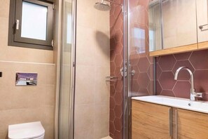 A modern bathroom with a glass shower enclosure, a white sink, and a toilet. - Red Bee Apartment Sea View (Nikiana)