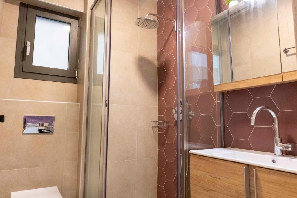 Ein Badezimmer mit Duschkabine aus Glas, einem Waschbecken mit modernem Wasserhahn und einem Holzkabinett.