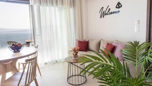 Un soggiorno moderno con un tavolo rotondo, un divano con cuscini e un cartello con la scritta 'Welcome' al muro.