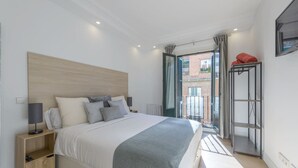 Ein modernes Schlafzimmer mit einem großen Bett, Nachttischen und einem Ausblick durch eine Glastür.