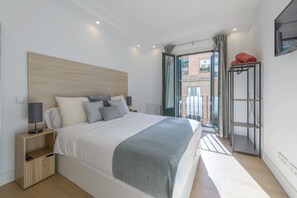 A modern bedroom with a large bed, bedside tables, a nightstand, and a view of the outside through a glass door. - Gran Vía, NEW, 2BR 1BTH. Elevator (Madrid)
