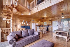 A wooden cabin interior with a sofa, dining table, and kitchen area. - Modern Retreat w/ Stunning Views & Hot Tub (Sevierville)