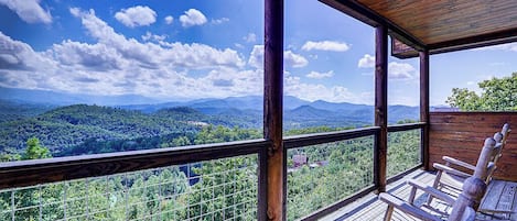 A wooden deck with a view of a forested mountain range.