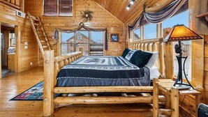 Ein Blockhauszimmer mit einem hölzernen Bett, einem Schreibtisch und einem Deckenventilator.