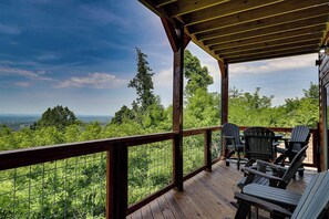 Eine Holzterrasse mit Blick auf einen Wald und Berge.