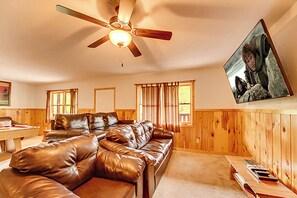 A cozy living room with a brown leather sofa, a wooden ceiling fan, and a television mounted on the wall. - Amazing Smoky Mountain Views w/ Hot Tub (Sevierville)