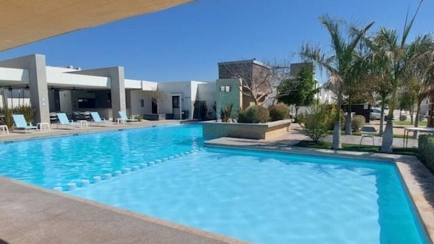 Ein Schwimmbecken mit Liegestühlen und einem Gebäude im Hintergrund.