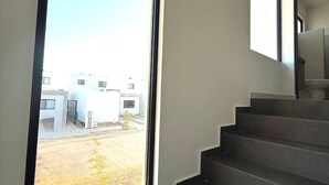 Ein modernes Interieur mit einem großen Fenster, einer Treppe und Blick auf ein Gebäude.