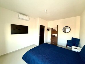A bedroom with a bed, a dresser, a chair, a mirror, and a TV. - Cozy Modern Retreat with Pool (La Paz)