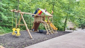 Puisesta materiaalista valmistettu keinuteline ja liukumäki metsäisellä alueella.