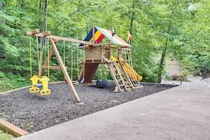 Ein hölzernes Schaukel- und Rutschspiel in einem Waldgebiet.